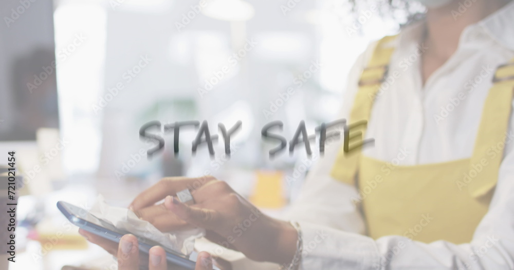 Image of flashing words with woman disinfecting smartphone in office wearing face masks Image of flashing words with woman disinfecting smartphone in office wearing face masks