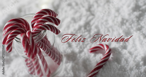 Feliz navidad text with christmas candy canes on snow background