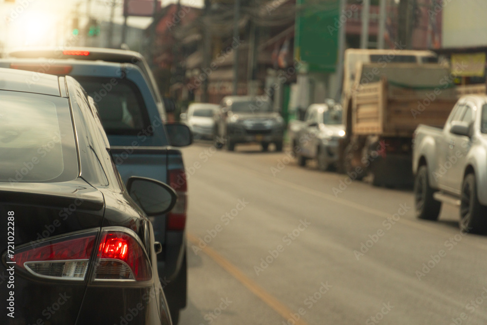 Rear side of black car with turn on brake light. Stop in line at an intersection with traffic lights on asphalt road. Various cars were lined up along the side of the city road. Rear side of black car with turn on brake light. Stop in line at an intersection with traffic lights on asphalt road. Various cars were lined up along the side of the city road.