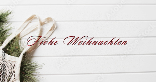 Frohe weihnachten text in red over shopping bag with christmas bracnhes on white wood background