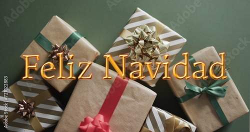Feliz navidad text in orange over christmas gifts on green background