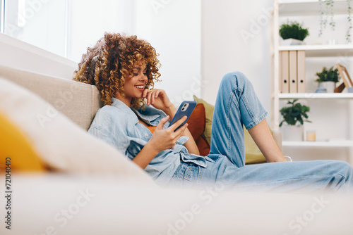 Happy Woman Holding Phone and Relaxing on Sofa at Home photo