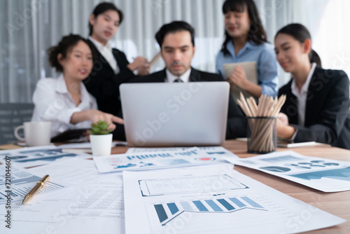 Focus financial data dashboard paper by business intelligence display graph  chart and statistic report on office table with blurred business people working in background. Habiliment