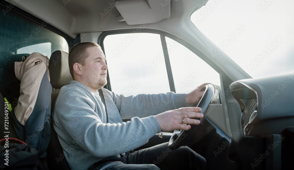 young charismatic male truck driver driving a car.