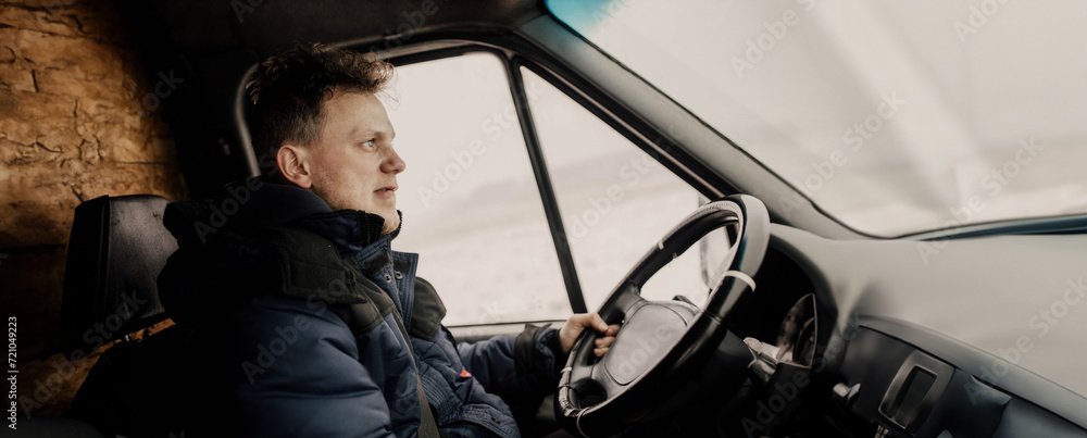 male truck driver driving in uniform in winter.