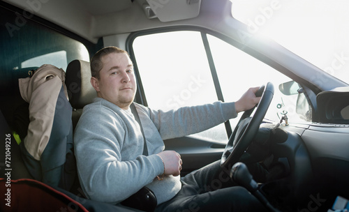 young charismatic male truck driver driving a car. © velimir