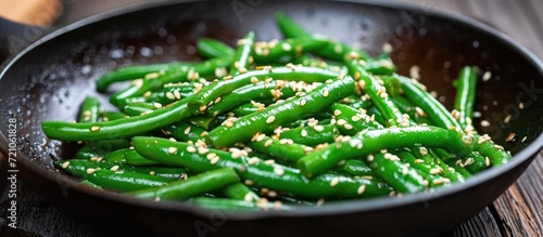 Green beans and sesame seeds cooked in a frying pan. photo
