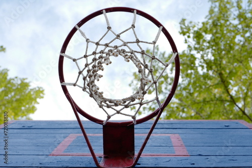 Basketball hoop outdoors against the sky, viewed from bottom up