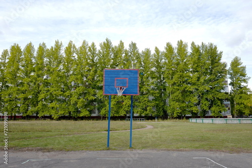 Basketball hoop on an outdoor basketball court with trees in the background