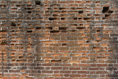 Background from an old brick wall with bricks falling out in some places photo