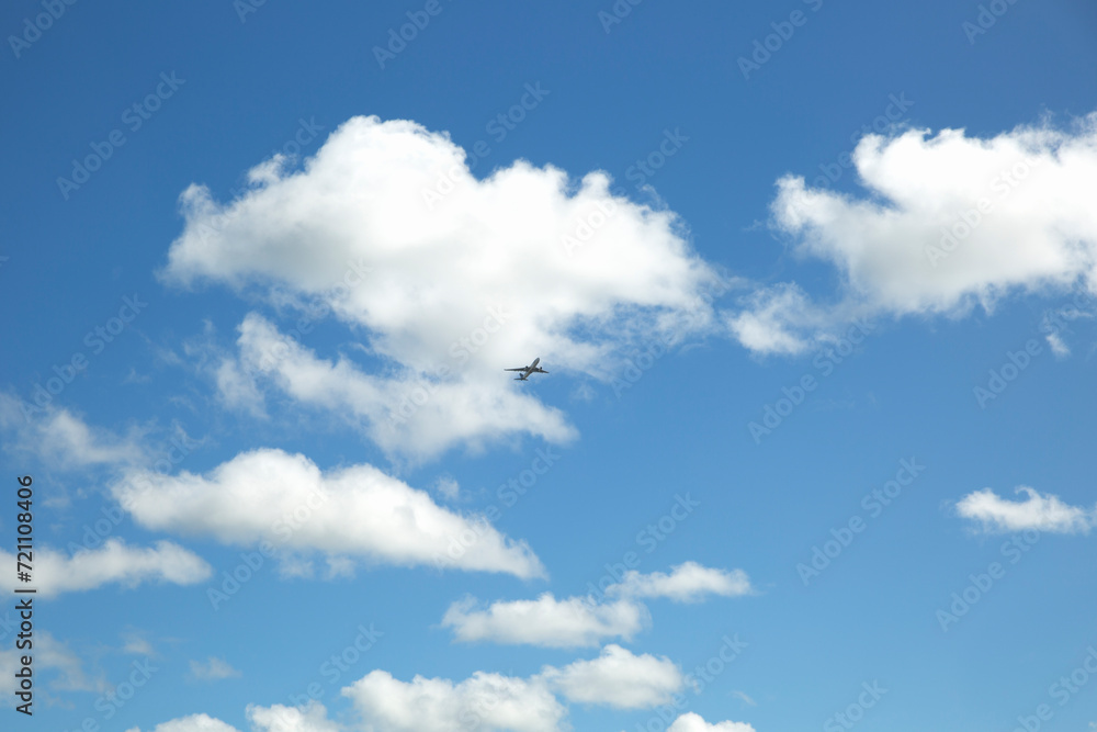 A plane in the blue sky with white clouds.