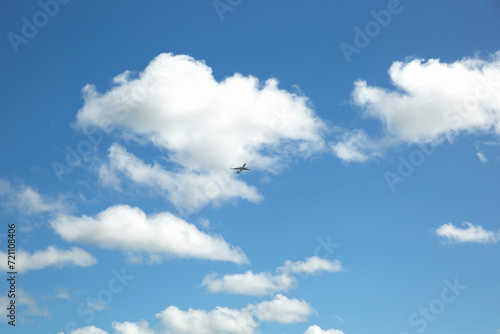A plane in the blue sky with white clouds.