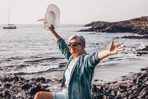 Cuadro en lienzo Happy carefree senior woman holding a white hat looking at new day from sea beac