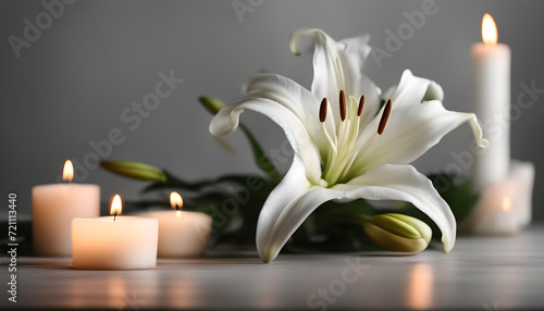 White lily and blurred burning candles on table in darkness