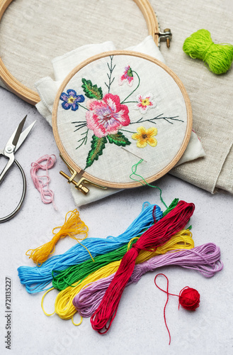 Bild auf Leinwand The process of hand embroidering a napkin with colored threads on white fabric