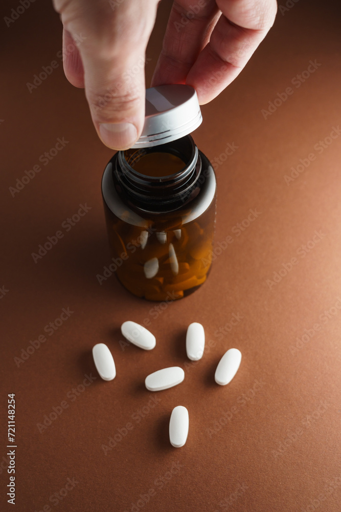 Białe tabletki rozsypane luzem z butelki z lekami - obrazy, fototapety, plakaty 
