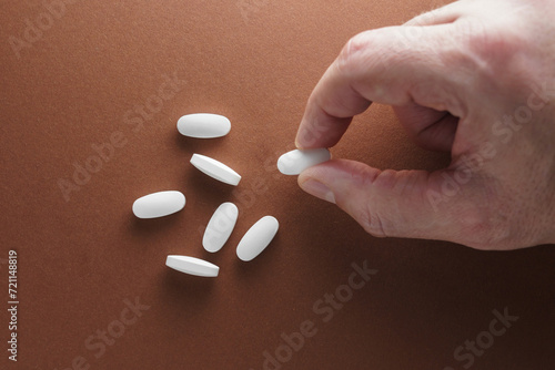 Tabletki na dłoni, ręka trzymająca pigułkę