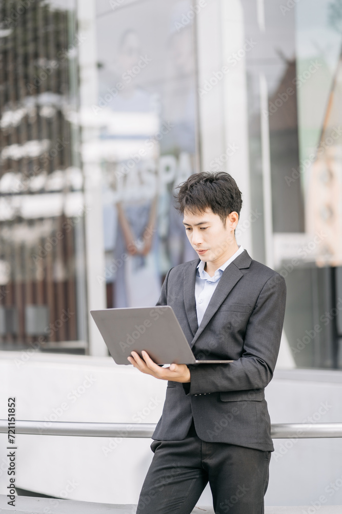 Asian male businessman use smartphone and holding laptop computer, Walk enjoy smiling while doing commuting at business center. Asian male businessman use smartphone and holding laptop computer, Walk enjoy smiling while doing commuting at business center.