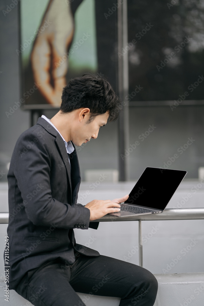 Asian male businessman use smartphone and holding laptop computer, Walk enjoy smiling while doing commuting at business center. Asian male businessman use smartphone and holding laptop computer, Walk enjoy smiling while doing commuting at business center.