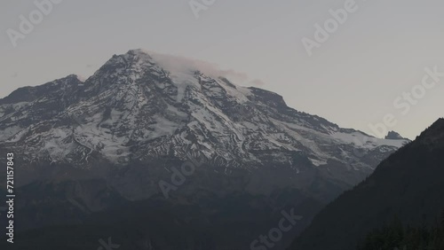 Ungraded aerial footage of Mt. Rainier at dawn just as sunrise begins to illuminate the morning sky in a soft, warm glow on a sunny autumn morning in Washington State.