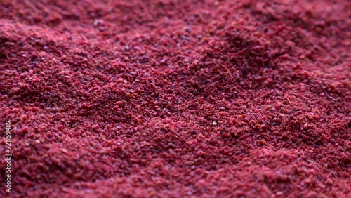 Red sumac spice powder circle rotation close up photo
