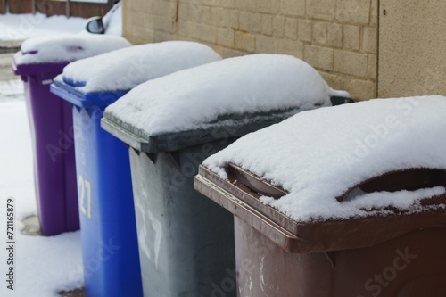 snow on a row of garbage bins