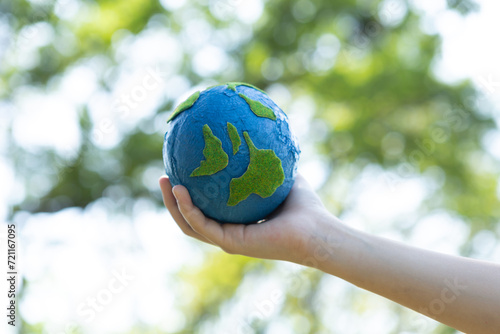 Fototapeta Naklejka Na Ścianę i Meble -  Young boy's hand holding planet Earth globe at natural park background as Earth day to save this planet with ESG principle and environment friendly energy for brighter future. Gyre