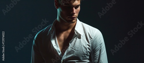 Stylish Young Man in a White Shirt on a Dark Background: Captivating Image of a Young Man in a Sleek White Shirt Standing Against a Dark Background photo