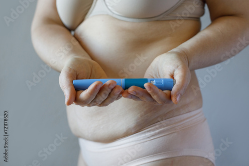Blue Semaglutide Injection pen closeup. Semaglutide or insulin drug against female model belly. Semaglutide, Diabetes and Weight Loss concept.