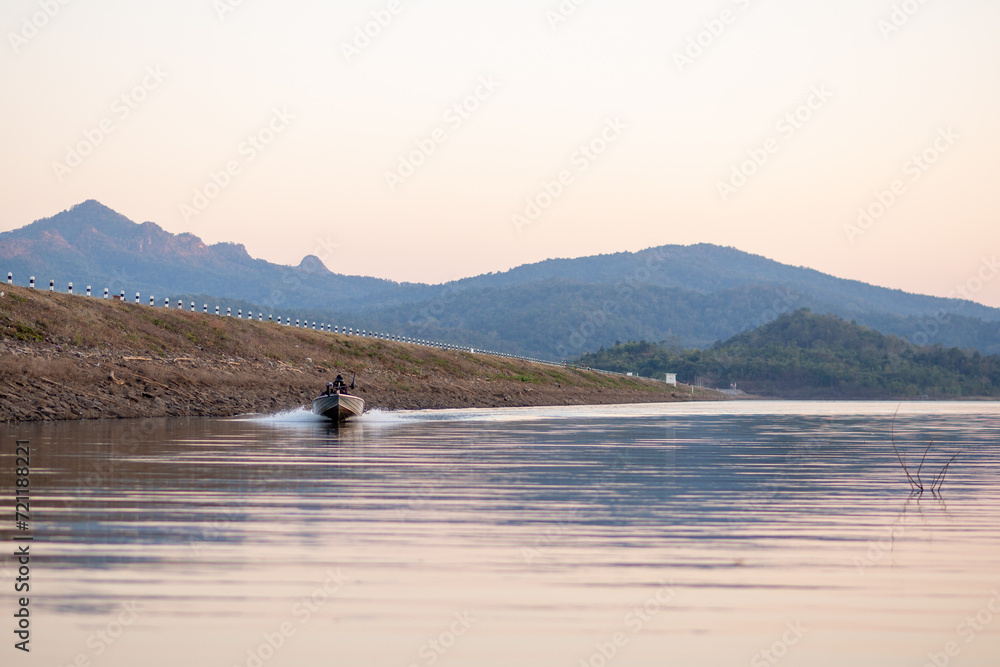 Fishing by the serene lake surrounded by majestic mountains under a clear sky