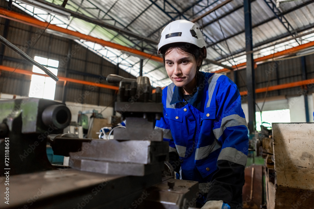 Asian female workers wearing uniform safety and hardhat working an iron cutting machine in factory Industrial. Engineering worker man work machine lathe metal. Heavy industry concept.