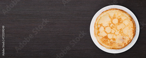 Banner of a round dish with fried pancakes on a brown table. Sweet dessert. Top view.
