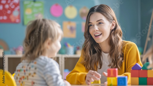 Young European woman teacher speech therapist in class talking with child, explain the letters. Therapist learning practice pronunciation exercises with child