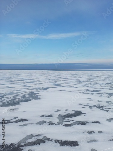 View from above. Blue sky  the surface of a frozen river covered with snow.