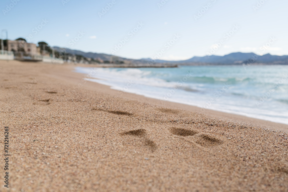 Footsteps on a sand beach of South France during spring with sea waves