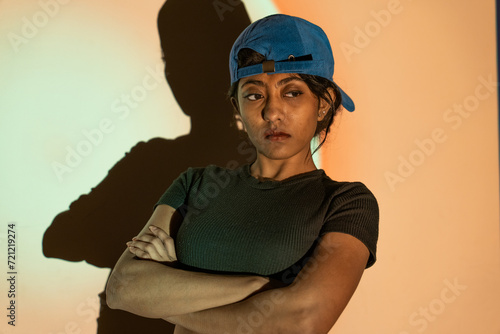 a multi-racial girl with a blue hat and a black T-shirt looking in the aggressive way with high attitude © oybekostanov