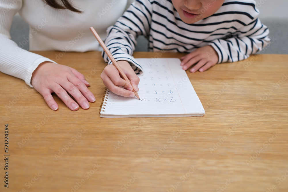 お母さんと一緒に勉強する小学生の男の子の手元のクローズアップ