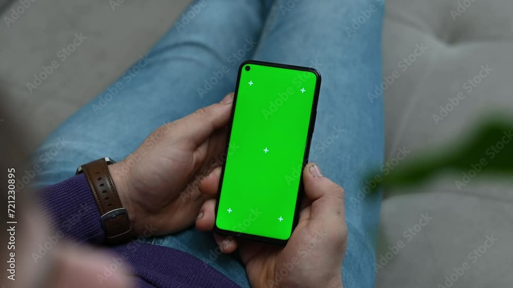 A man holds a phone with a green Chroma Key screen mockup for web surfing, watching video blogs, touching the center screen. Close-up. 4K slow motion footage A man holds a phone with a green Chroma Key screen mockup for web surfing, watching video blogs, touching the center screen. Close-up. 4K slow motion footage