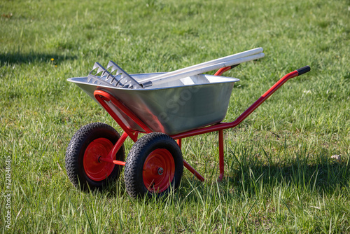 A hand cart on wheels with a garden tool.