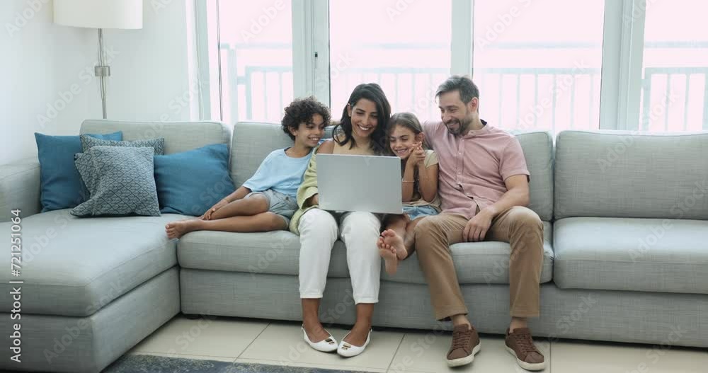 Happy preteen sibling children and Latin couple of parents resting on spacious couch with laptop at home, watching movie, video, using online service for entertainment, leisure Happy preteen sibling children and Latin couple of parents resting on spacious couch with laptop at home, watching movie, video, using online service for entertainment, leisure