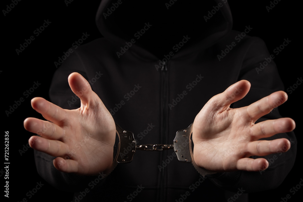 Unknown, indistinguishable thug or hucker in handcuffs and black clothes is arested.