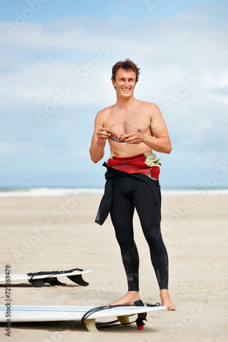 Photography Surfer, man and face or happy with surfboard on beach with wetsuit, blue sky and confidence with sunglasses