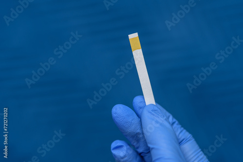 Izolowany papierek lakmusowy do badania odczynu pH trzymany w dłoni 