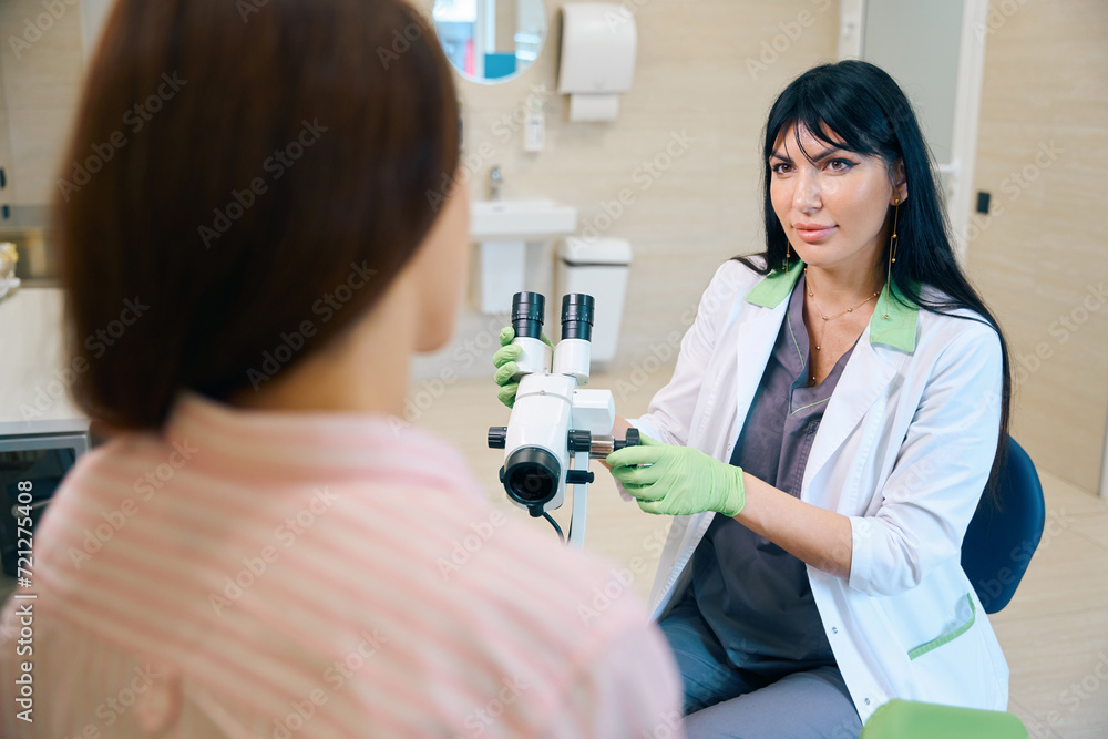 Female gynecologist with microscope looking at partial woman patient Female gynecologist with microscope looking at partial woman patient