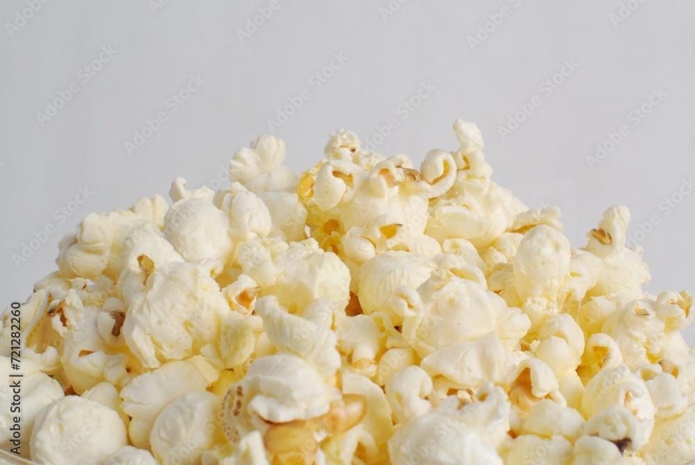 Popcorn in a glass bowl, isolated on white background.