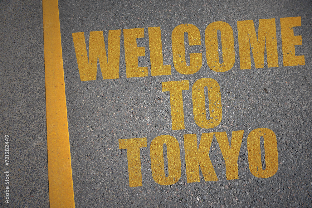 asphalt road with text welcome to Tokyo near yellow line.