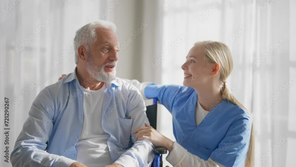 Nurse talking senior man in wheelchair. Woman social welfare physical therapist looks after senior male, listening, providing medical care at clinic. Living with legs paralysis, special needs people. Nurse talking senior man in wheelchair. Woman social welfare physical therapist looks after senior male, listening, providing medical care at clinic. Living with legs paralysis, special needs people.