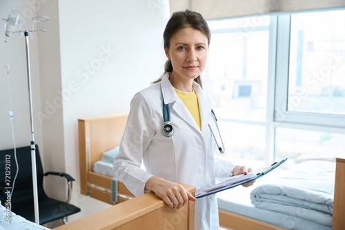 Front view of female doctor with clipboard looking at camera in clinic