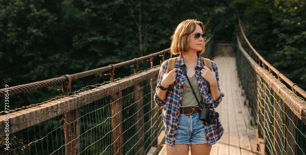 Beautiful young female traveler with backpack walking by the scenic bridge Beautiful young female traveler with backpack walking by the scenic bridge