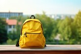 Backpack with various colorful stationery on the table on blurred nature town background